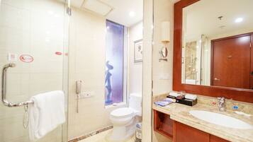 A modern bathroom with a glass shower enclosure, a white toilet, a sink with a mirror, and a towel rack.