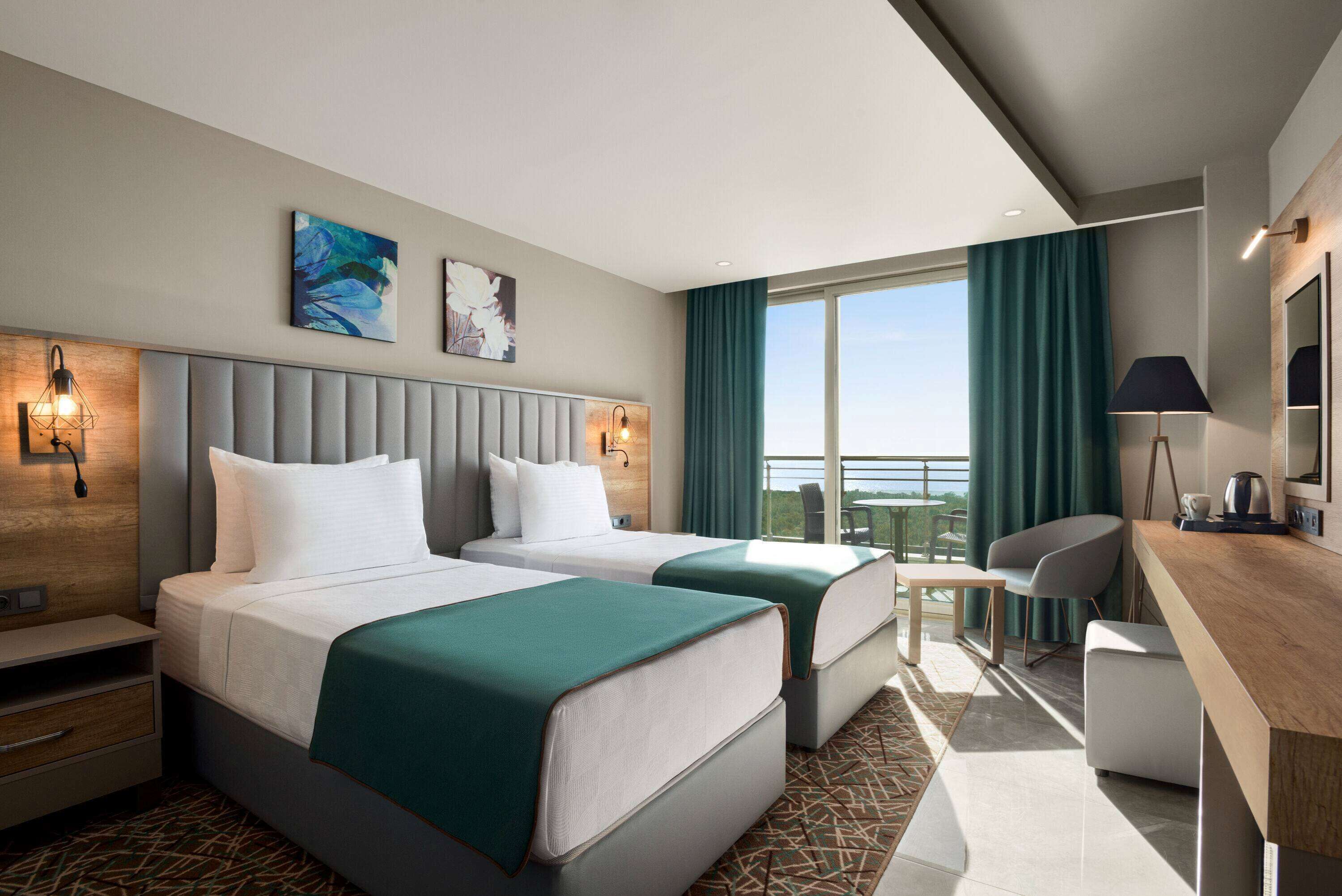 Habitación de hotel moderna con dos camas, un escritorio y un balcón con vistas.