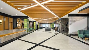 A spacious lobby with a high ceiling, a reception desk, seating area, and a staircase.