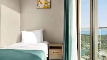 Un dormitorio con cama, mesita de noche, cajón, un cuadro y vista al océano.