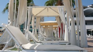 A beachside lounge area with white lounge chairs and a canopy structure.