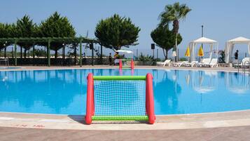 A swimming pool with a goalpost, lounge chairs, and a covered seating area.