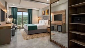 A modern hotel room with a bed, desk, and TV.