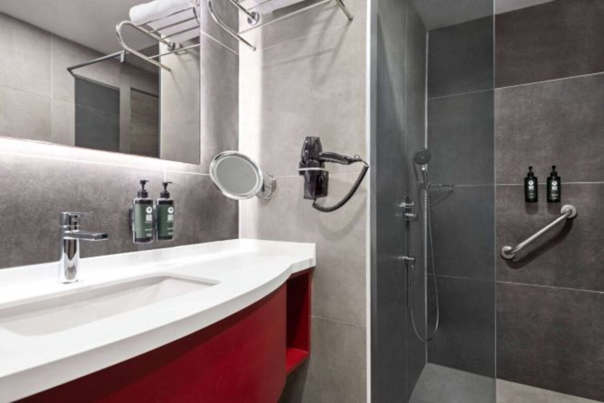 Een moderne badkamer met een wit wastafel, een ronde spiegel en een douche met een handdouche.