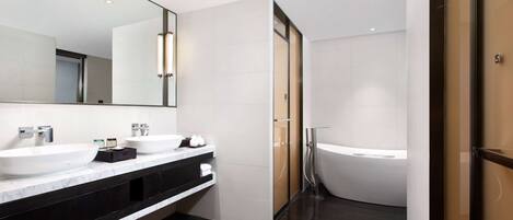 Een moderne badkamer met twee wasbakken, een grote spiegel en een vrijstaand bad.