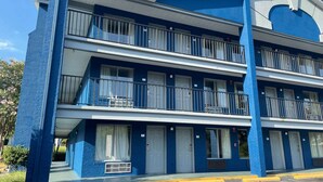 Een meerlaags hotel met een blauwe gevel, balkons op elke verdieping en een centrale trap.