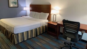Een hotelkamer met een bed, nachtlampjes, een bureau en een stoel.