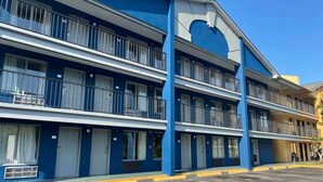 Een motel met meerdere verdiepingen, balkons, een blauwe gevel en een parkeerplaats.