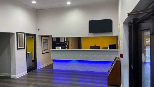 Een receptiezone met een balie, een wandtelevisie en een trap naar een hoger niveau.