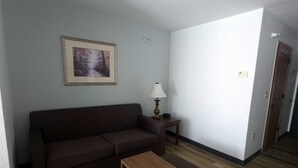 Una sala de estar con un sofá marrón, una mesa de centro de madera y una lámpara.