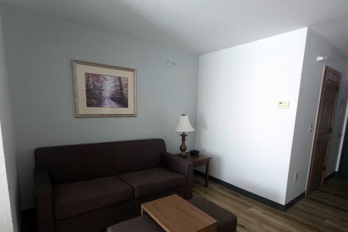 Ein Wohnzimmer mit einem braunen Sofa, einem Holztisch und einer Lampe.