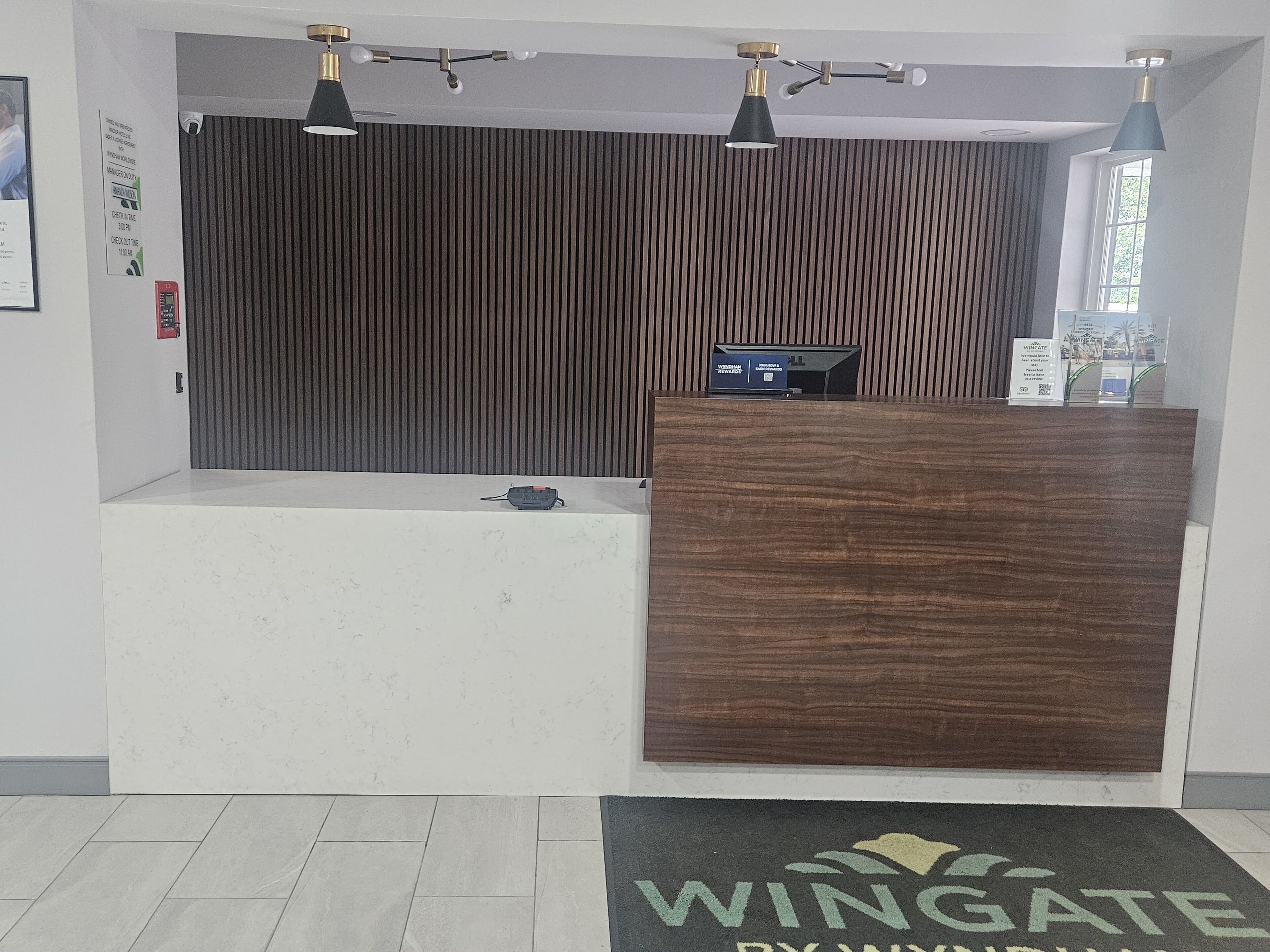 A reception desk with a wooden finish, a black and white check-in counter, and a wall-mounted security camera.