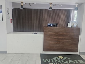 Una recepción con mostrador de madera, un mostrador de recepción a cuadros blanco y negro y una cámara de seguridad montada en la pared.