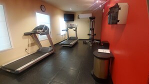 Un gimnasio con cintas de correr, escaladora y máquina de pesas.