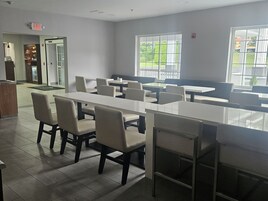 A spacious indoor area with multiple seating arrangements, including tables and chairs, and a visible exit sign.