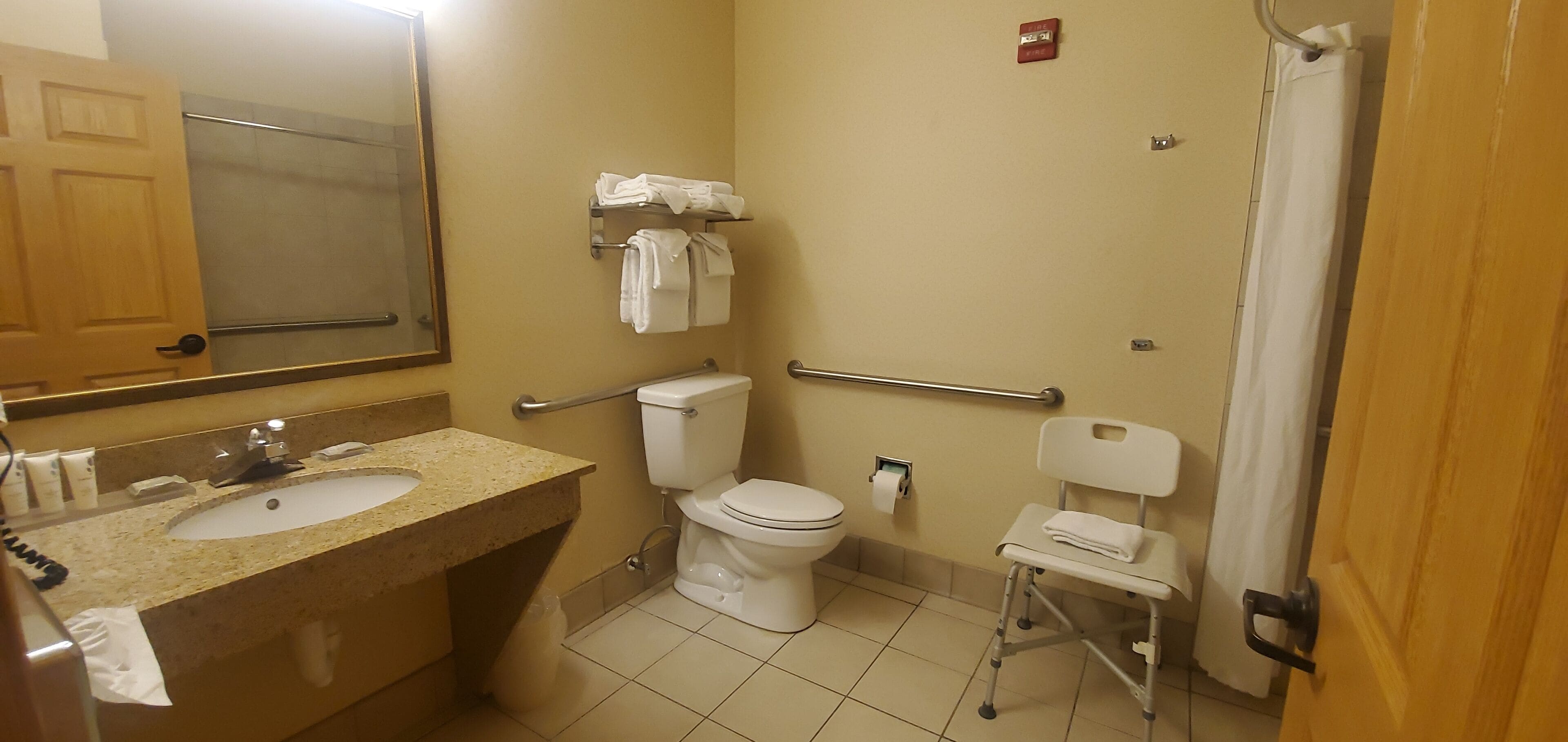 A bathroom with a sink, toilet, and a wheelchair-accessible chair.