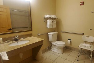 Un baño con lavamanos, inodoro y barras de apoyo.