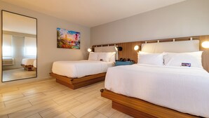 Une chambre d’hôtel avec deux lits, un grand miroir, un tableau et une tête de lit en bois.