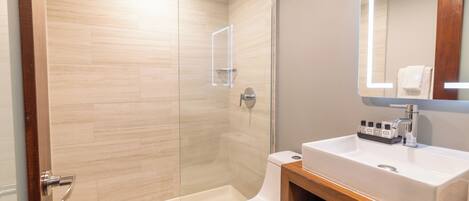 A modern bathroom with a glass-enclosed shower, a white toilet, and a wooden vanity with a sink.