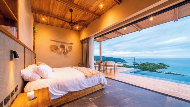 A bedroom with a bed, bedside table, and a view of the ocean. - LALOON Luxury Suites - Adults Only, Santa Teresa Beach (Santa Teresa)