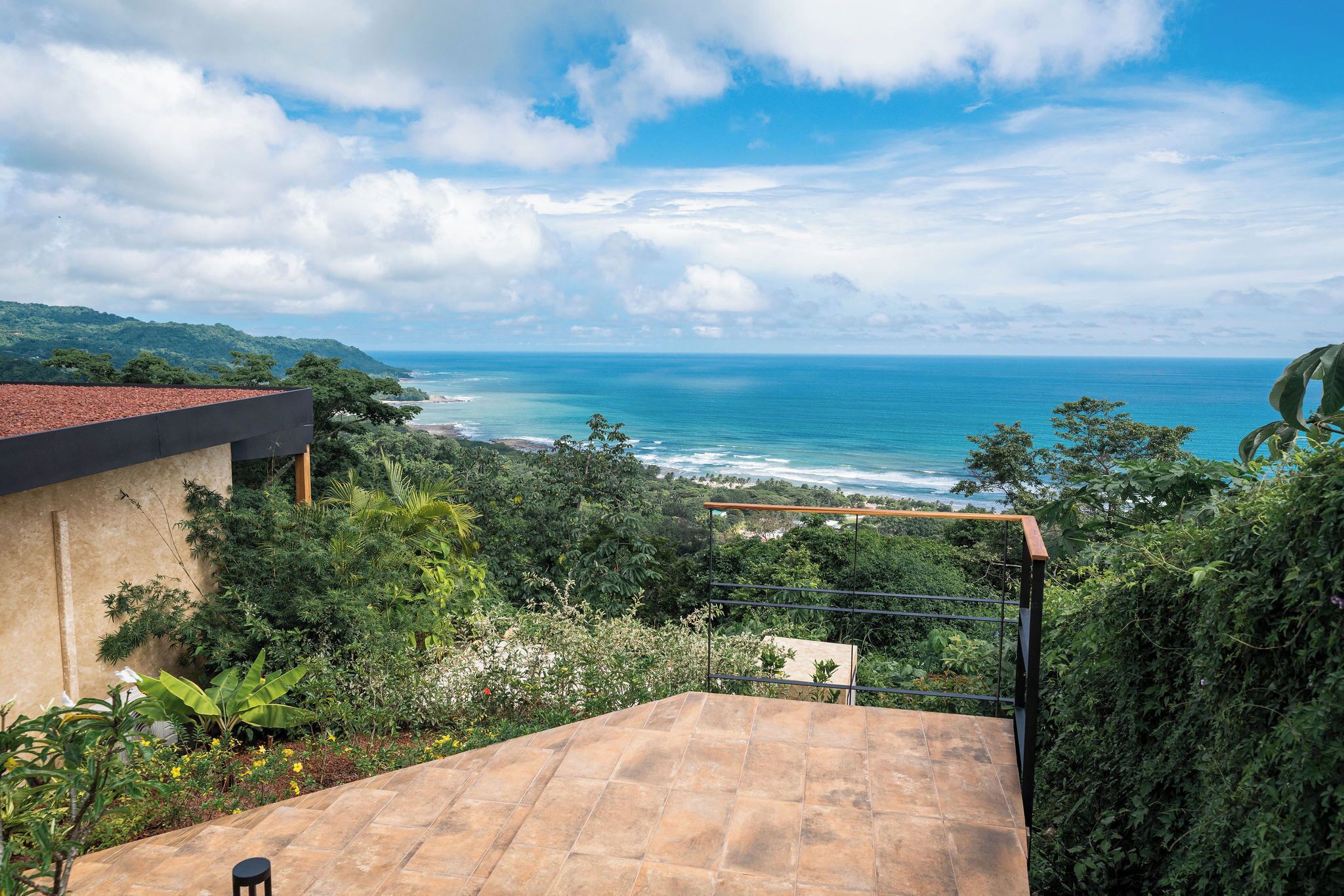 A terrace with a view of the ocean and surrounding greenery.