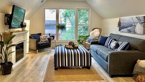 Een gezellige woonkamer met een open haard, een televisie, een bank en een groot raam met uitzicht op de omgeving.