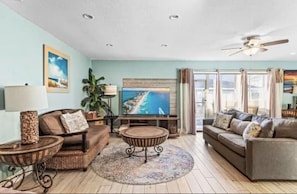 Relax in this cozy living space with a large flat-screen TV, comfortable seating, and a ceiling fan.
