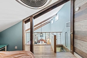 Relax in a spacious room with a large bed, circular window, and access to a balcony with a view.