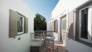 Een balkon met een tafel, stoelen, een klein raam en een deur.