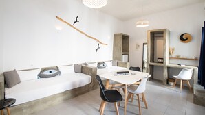 Een moderne woonkamer met een bank, eettafel, stoelen en een hanglamp.