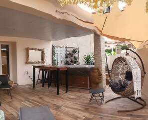 A cozy indoor space with a wooden floor, a dining table, a sofa, and a hanging chair.