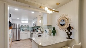 A modern kitchen with white cabinets, a large island, and a unique wall decoration. - Well-Appointed Family Summer Home - King Bed - Close to DEN & Anschutz (Aurora)