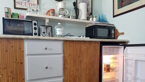 A compact kitchen with a microwave, toaster, and coffee maker on the countertop.