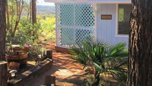 A small cottage with a sign reading "COTTAGE" on the door, surrounded by trees and plants.
