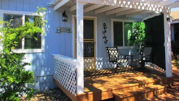 A house with a covered porch, a small patio area, and a window with shutters.