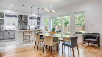 A modern kitchen with white cabinets, a central island, and a dining area with chairs.
