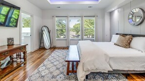 Um quarto com uma cama, ventoinha no teto, uma janela grande e vista para o exterior.