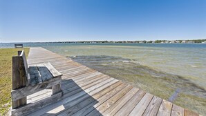 A wooden pier extending into a calm body of water with a clear sky above. - Compass Point 310 (Gulf Shores)