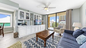 A spacious living area with a sofa, coffee table, and a view of the ocean through large windows. - Compass Point 310 (Gulf Shores)