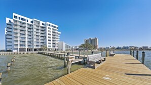 A wooden pier extending into calm water, leading to a white multi-story building with balconies. - Compass Point 310 (Gulf Shores)