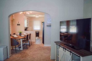 Un espace de vie compact comprenant un coin repas, une kitchenette et un téléviseur posé sur un meuble en bois.
