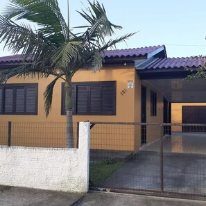 Experience a tropical ambiance in this two-story home with a fenced front yard and a palm tree.