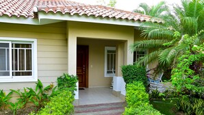 Une maison avec un toit en tuiles, une porte d’entrée et un petit jardin avec un chemin menant à l’entrée.
