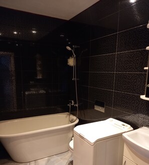 Une salle de bain moderne avec une baignoire sur pieds, des toilettes et un espace douche.