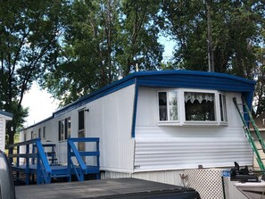 Situated in a wooded area, this home offers a front porch with a ladder leading up to the entrance.