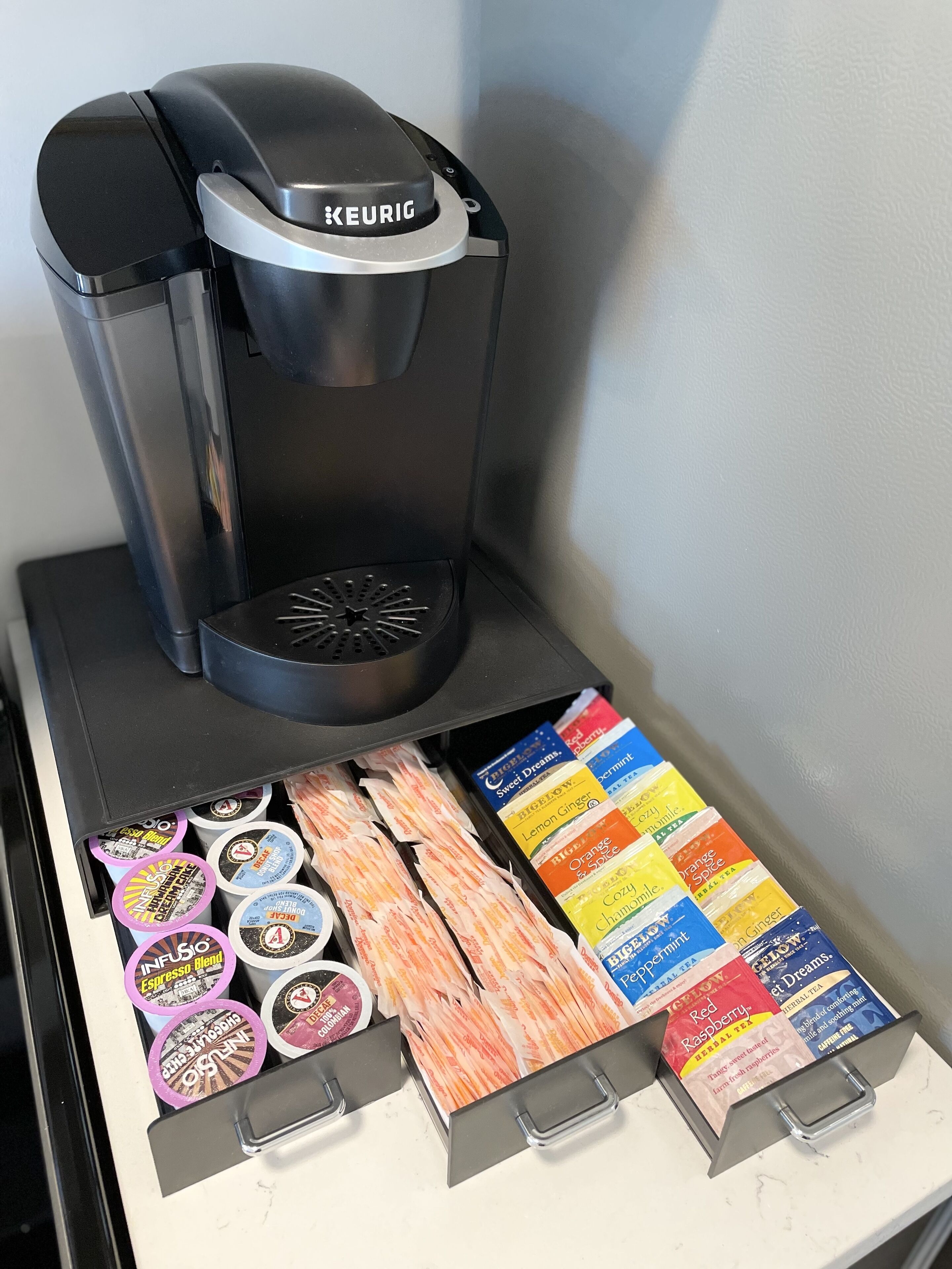 Una màquina de cafè Keurig amb una selecció de càpsules de cafè i bosses de te.