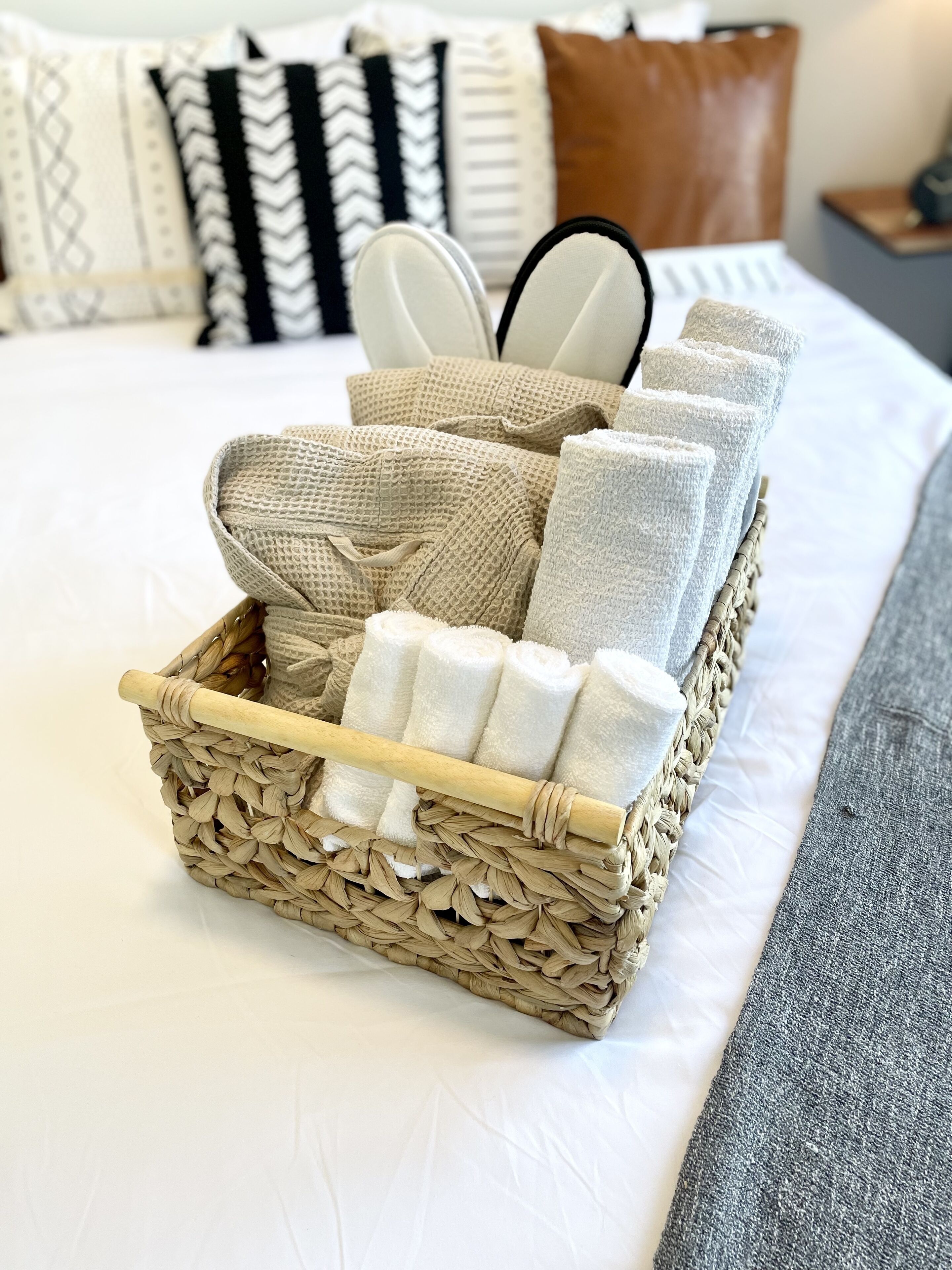 Una cesta de mimbre con toallas dobladas sobre una cama.
