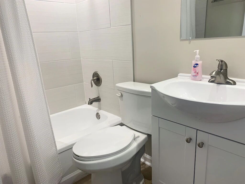 Un baño con inodoro y lavamanos blancos, además de una bañera.