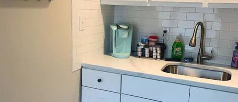 A kitchen with white cabinets, a stainless steel sink, and a countertop with various items.