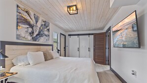 Um quarto moderno com uma cama grande, cabeceira de madeira e luminária no teto.